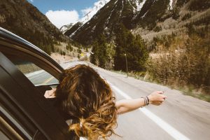 Femme passant la tête par la fenêtre d'une voiture en marche