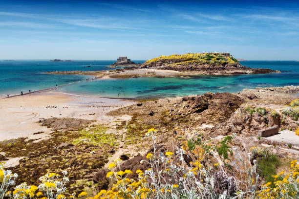 Plage de sable blanc en Bretagne avec eau turquoise et presqu'île rocheuse